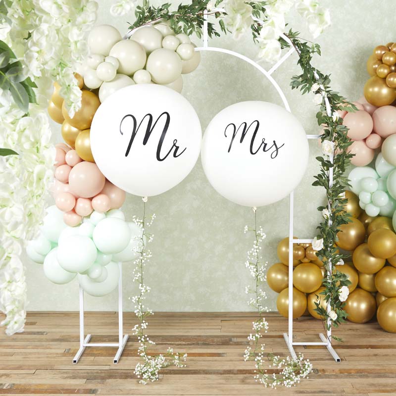 White Mr and Mrs balloons framed by flowers, greenery and pastel wedding balloon garlands.